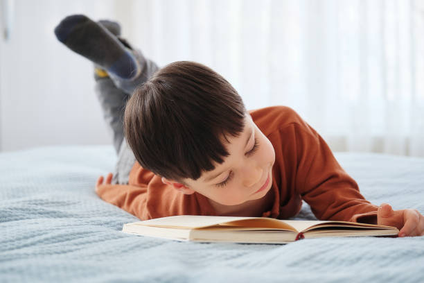 istock 4-5 years old child reading book at home. Lying down at bed 1311471620