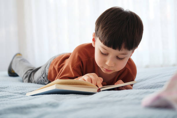 istock 4-5 years old child reading book at home. Lying down at bed 1311471626