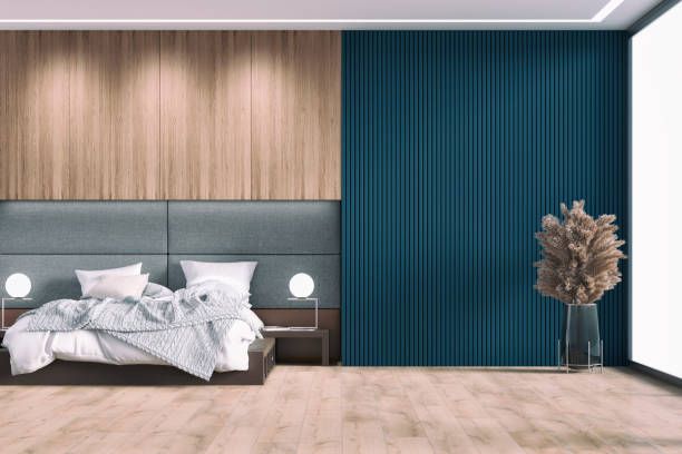 Luxury bedroom with decoration and copy space Luxury bedroom with a gray and brown leather headboard bed, night tables, lights and hanging closet on hardwood floor. A large dried pampas grass in a vase in front of a navy blue empty hardwood paneled wall with copy space and windows in the background. 3D rendered image. head board bed blue stock pictures, royalty-free photos & images