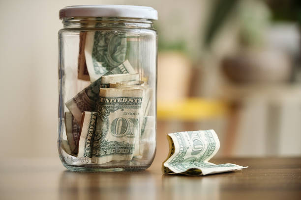 istock Saving money in a glass jar at home 1311473260