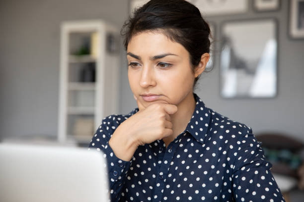 istock Indian businesswoman looks at laptop screen thinks over task 1311475013