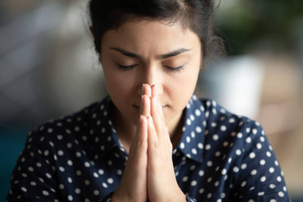 istock Closeup religious indian female closed eyes praying with folded palms 1311475038