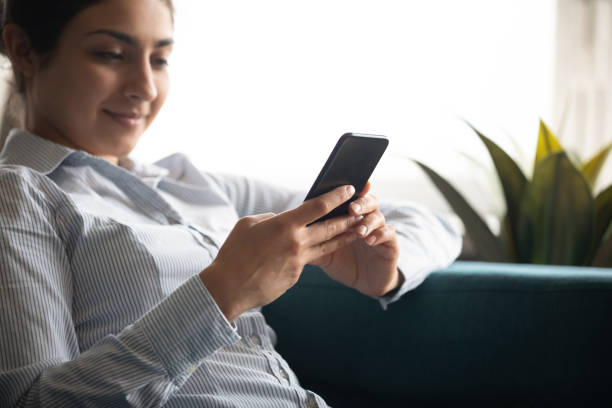 istock Indian woman relaxing on comfy sofa with smartphone closeup image 1311475114