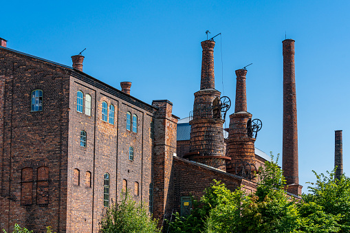 Old, run down, decaying, tall brick chimney of an abandoned urban power plant at dusk, no people.