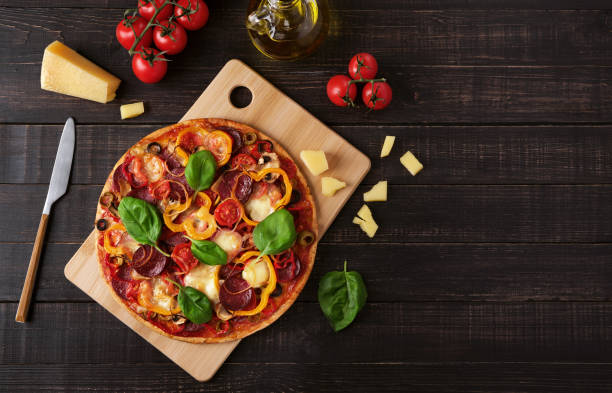 istock Pizza with mozzarella and salami on a dark wooden background 1311478910