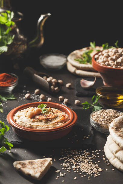 istock Classic hummus in a bowl with ingredients on dark background. Vertical format. 1311479137