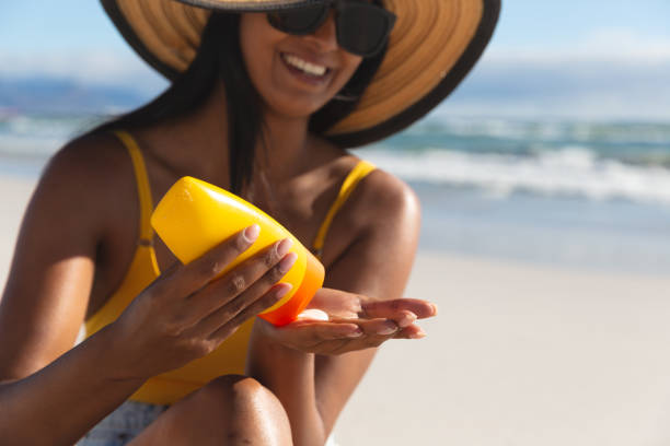 istock Smiling mixed race woman on beach holiday using sunscreen cream 1311479541