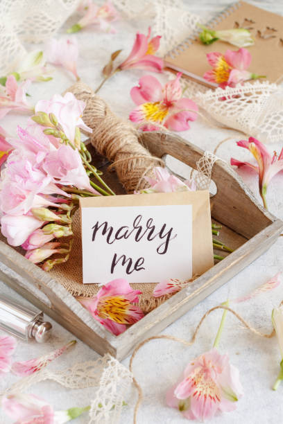 istock MARRY ME card on a white table between pink flowers 1311479560