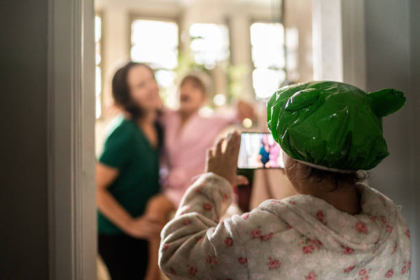 niña filmando a madre y hermana cantando en el baño - little girls women red bathroom fotografías e imágenes de stock