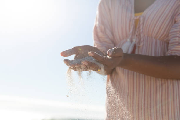 istock Mixed race woman on beach holiday spilling sand 1311484508