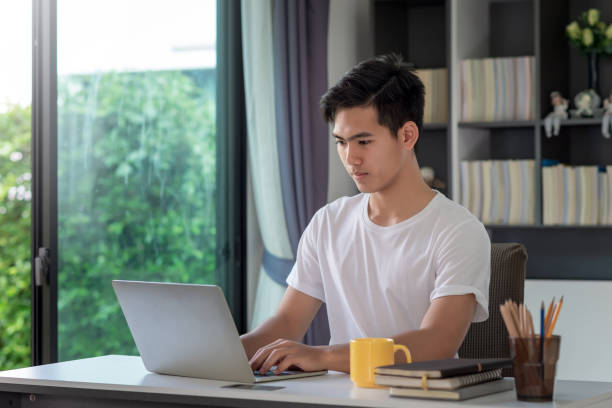 istock Image of a young Asian man working at home using a laptop on a coffee at table. 1311485127