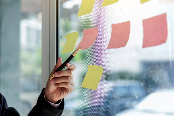 istock Close up hand businessman writing sticky notes on glass wall in office. 1311485177
