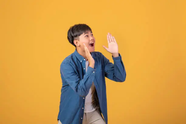 Photo of On orange background With a young Asian man Happy standing