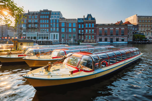 日没時にアムステルダム運河桟橋に係留された観光船 - 遊覧船 ストックフォトと画像