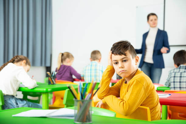 istock Portrait of tired schoolboy sitting in classroom elementary school 1311486475