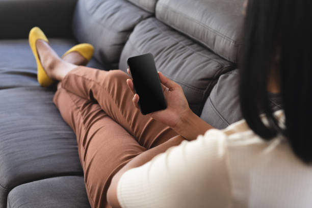 istock Mixed race gender fluid man relaxing at home on couch using smartphone, with copy space screen 1311491094
