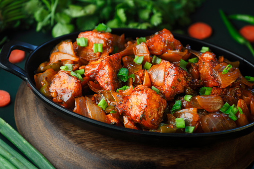 Spicy Paneer or chilli paneer or cottage cheese, served in black Dish with capsicum and onion