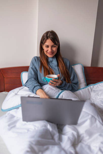 istock Woman working on laptop computer and drinking tea in bed 1311492899