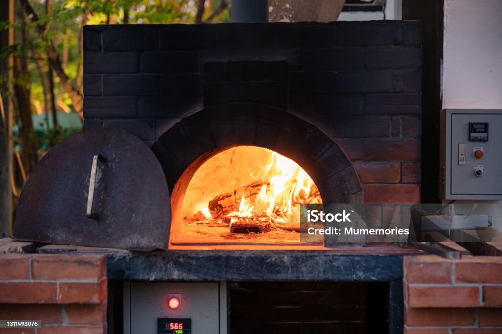 Firewood burning in pizza stove at pizzeria Firewood burning in traditional pizza stove at pizzeria Oven Stock Photo