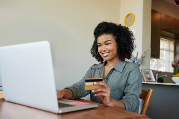 A woman holding her credit card while using her laptop