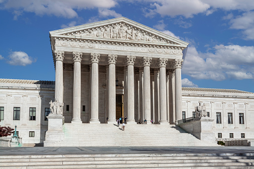 U.S. Supreme Court Building, Washington DC, USA. Blue sky with Puffy Clouds is in background. \n.