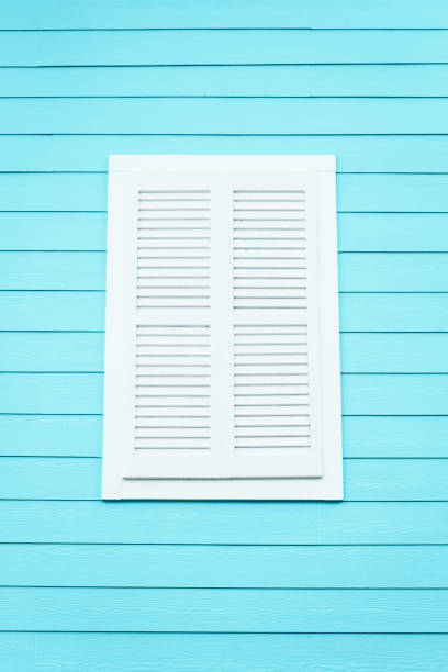 White Louvered Window Shutter on a Light Blue Wooden Building