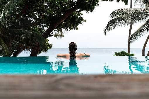 Young adult woman relaxing in a swimming pool