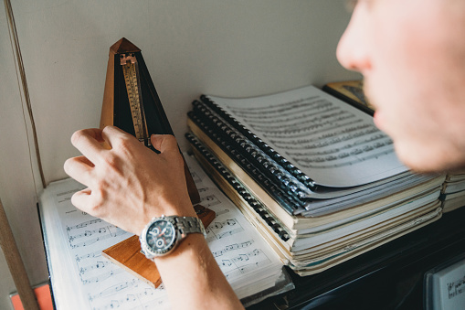 Young adult pianist starting the metronome