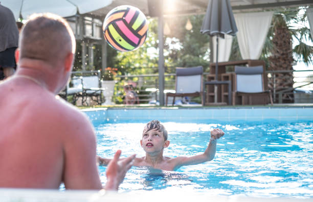 istock Boy playing with a ball in the swimming pool 1311503040