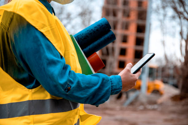 woman civil engineer using phone app to call a cab in the rain - female construction telephone building contractor imagens e fotografias de stock