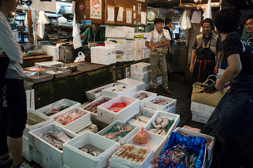 Horizontal view of some fishmongers chatting and laughing around their merchandising in the Seafood Intermediate Wholesalers' Area, Tsukiji Market, Tsukiji district, Tokyo