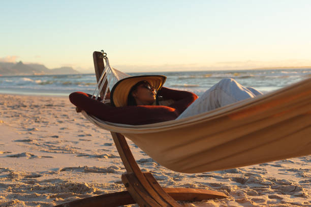 istock Mixed race woman on beach holiday lying in hammock 1311504761