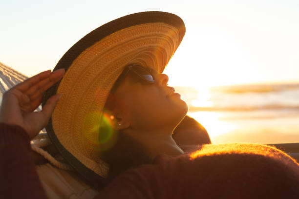 istock Mixed race woman on beach holiday lying in hammock during sunset 1311504790