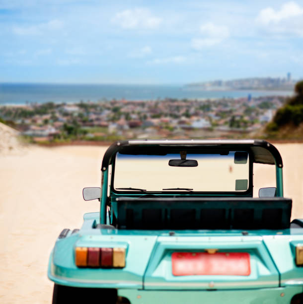 Rear view of a beach buggy parked on a sand dune over looking a seaside town