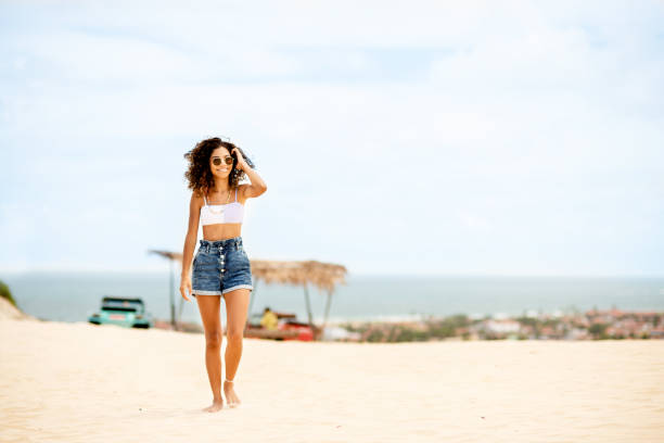 smiling teen girl walking on a beach in summer - halter top imagens e fotografias de stock