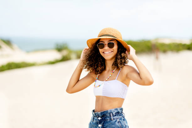 smiling teen girl standing on a beach in summer - halter top imagens e fotografias de stock