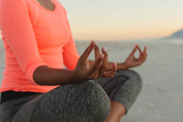 istock Middle section of mixed race woman on beach practicing yoga meditating 1311505807