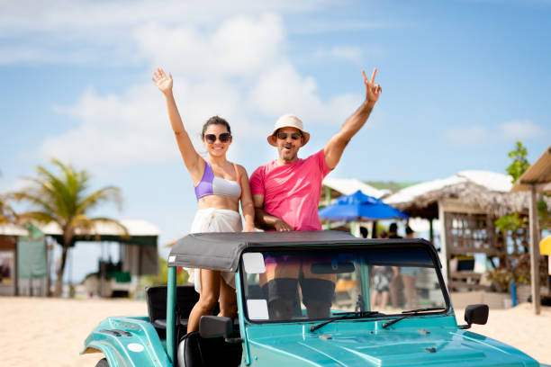 Smiling couple waving from the back of a beach buggy