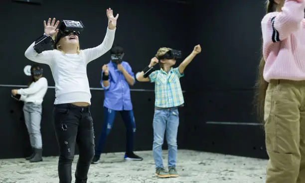 Photo of Excited tweens in VR glasses playing virtual reality games