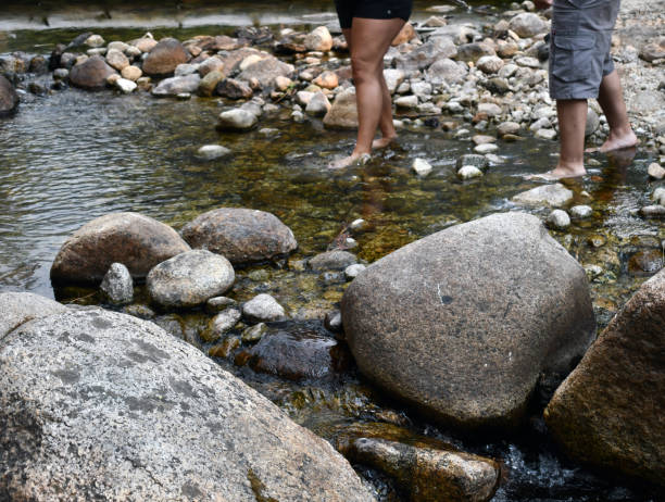 istock Two people with shorts crossing the rocky river 1311507641