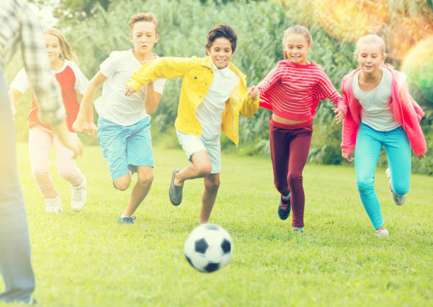 istock Kids playing football in park 1311509190