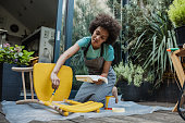 Woman paints an old chair in the back yard