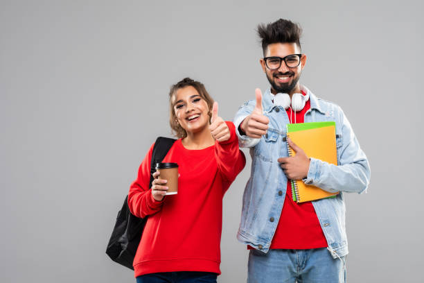 istock Young indian students with backpacks and books making thumb up gestures isolated on white background 1311512572