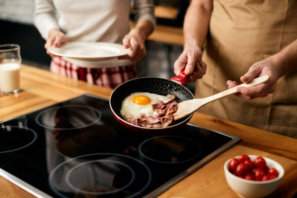 zbliżenie człowieka przygotowuje jajka sadzone z boczkiem na śniadanie w domu. - eggs fried egg frying pan fried zdjęcia i obrazy z banku zdjęć