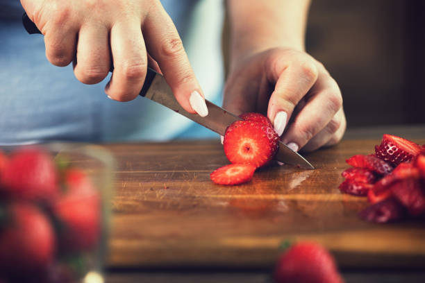 istock Young Women Cutting Fresh Strawberries 1311513757