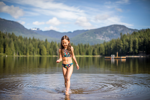 Girl in swimsuit playing by the lake.