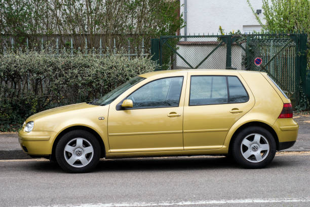 profilansicht des orangefarbenen volkswagen golf 4, der auf der straße geparkt ist - hatchback volkswagen golf volkswagen side view stock-fotos und bilder