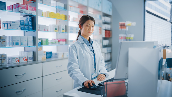 Portrait of trustworthy pharmacist standing against shelves and storage of antibiotics, pills, drugs, painkillers. Friendly healthcare professional ready to assist and help. Over the counter relief