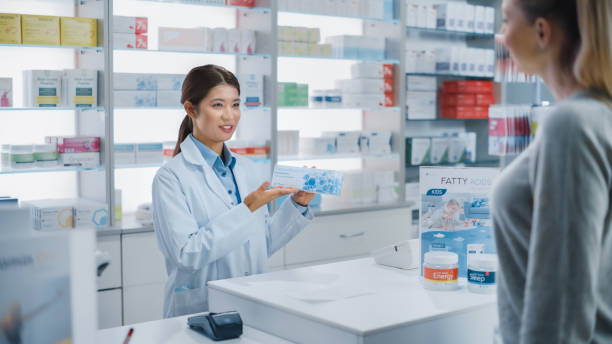 аптека аптека касса кассир счетчик: профессиональная азиатская женщина фармацевт рекомендует медицину в пакете для красивых кавказских ж� - cash register checkout counter customer shopping стоковые фото и изображения