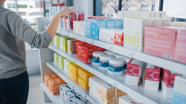 약국 약국: 익명의 여자는 선택하고 최고의 의학 패키지를 선택, 유연한 상자, 마약, 선반의 알약, 그녀는 그것을 사고 싶어. 현대 제약 상점 건강 관리 제품 - cosmetics retail shopping checkout counter 뉴스 사진 이미지